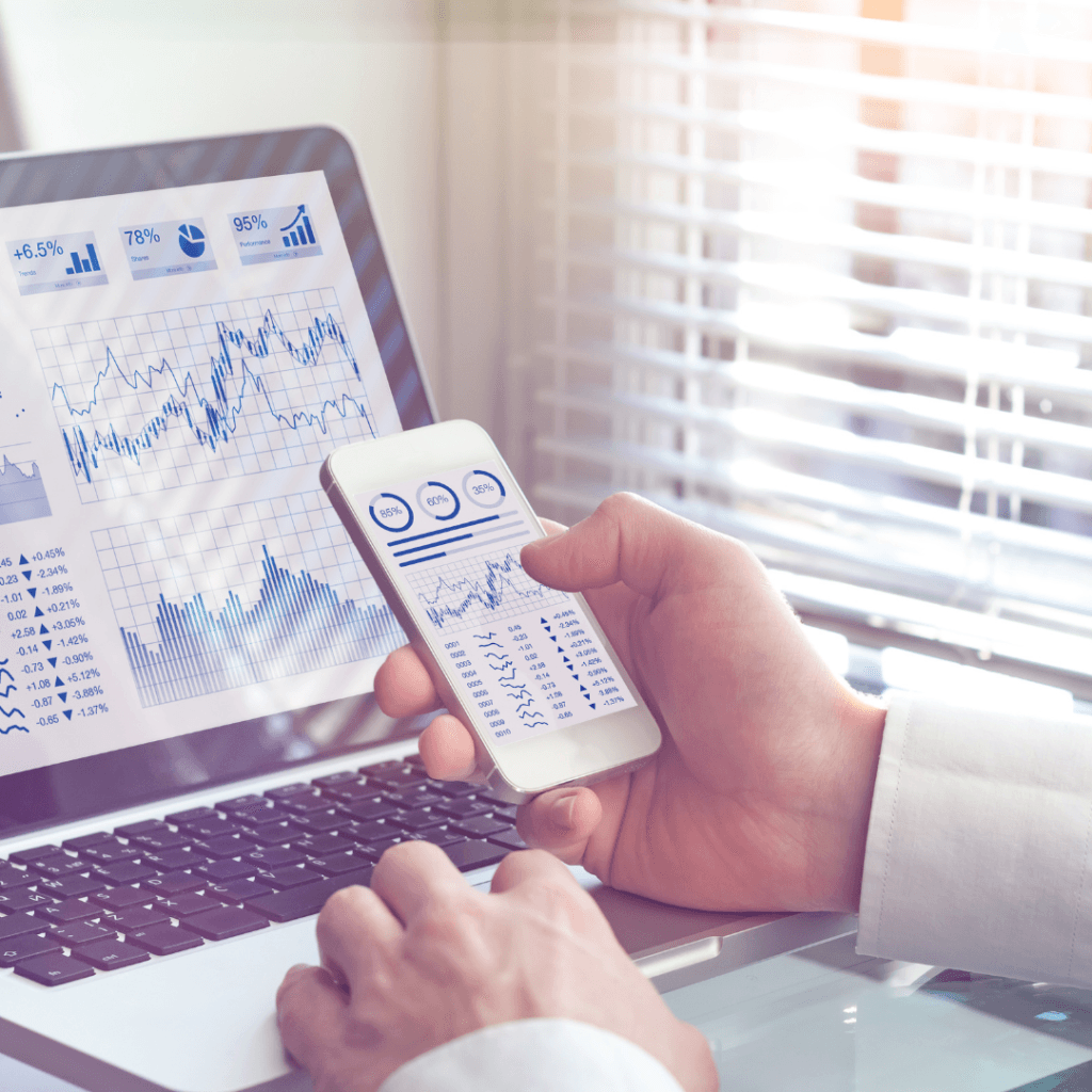man looking at data on a phone and laptop